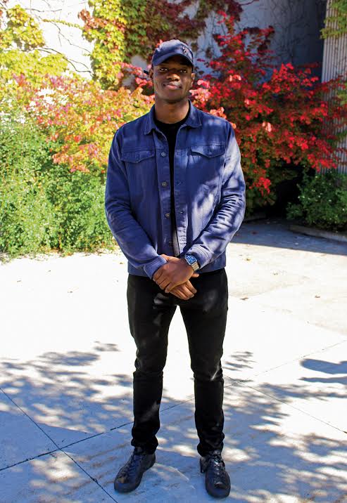 Student posing on campus wearing a denim jacket and black skinny jeans. 