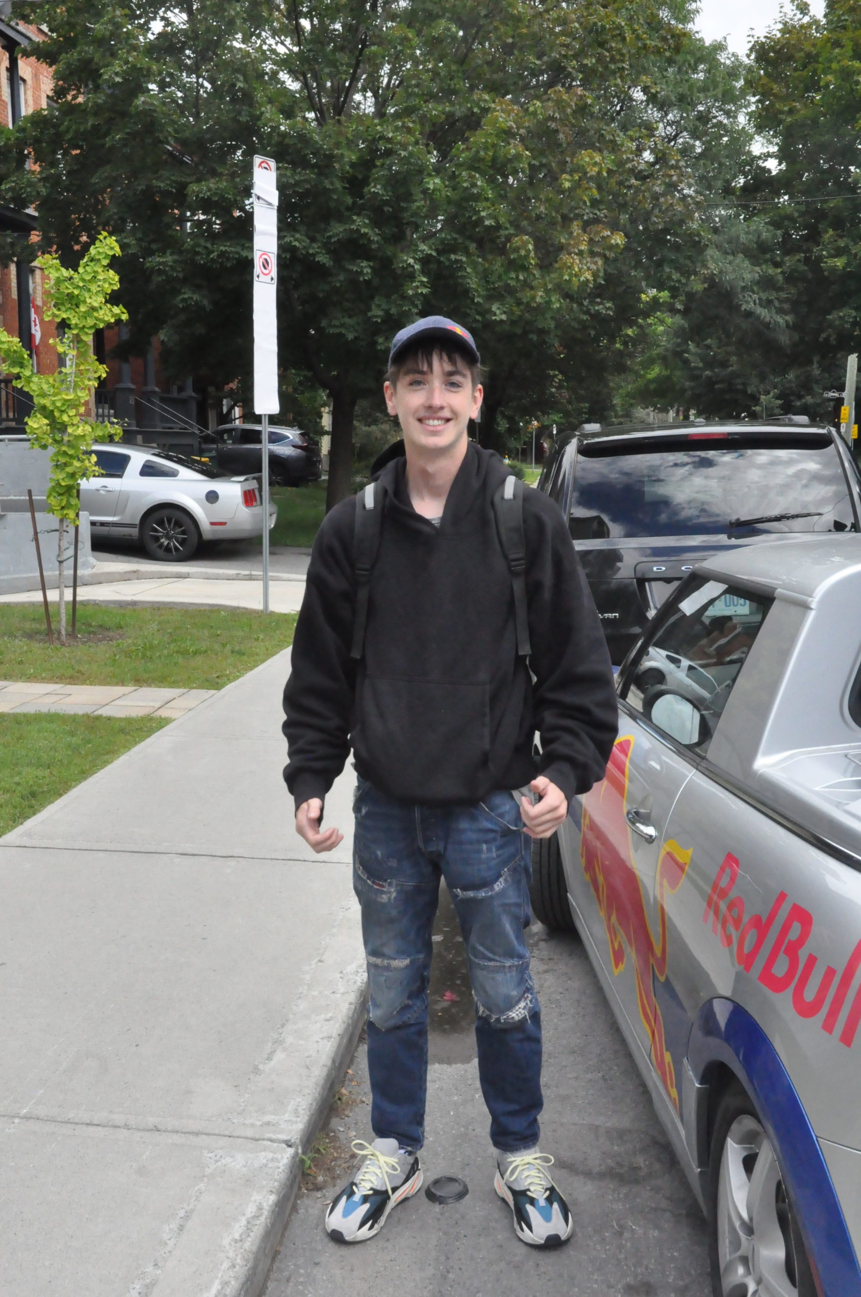 U of O student wearing a black hoodie, blue jeans, and shoes that pull together the colours of his outfit.