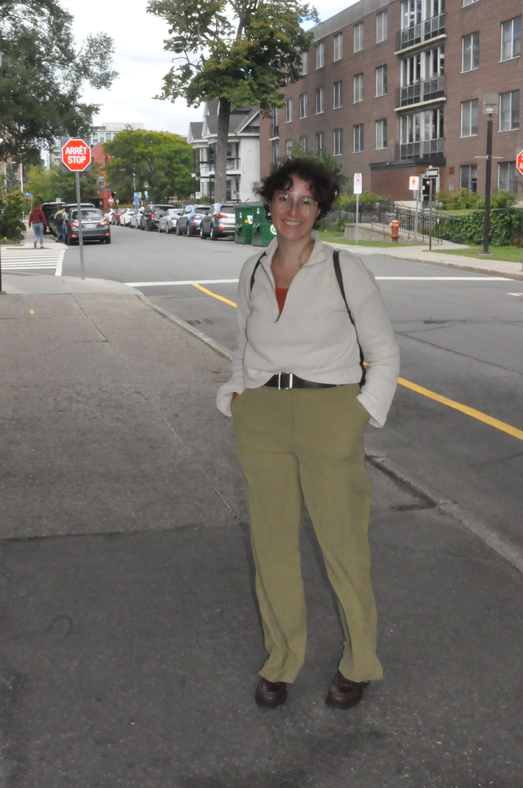 U of O student wearing green workwear pants with a white sweater and brown boots.