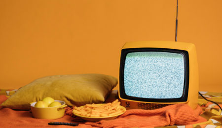 Photo of yellow television and snacks with orange background