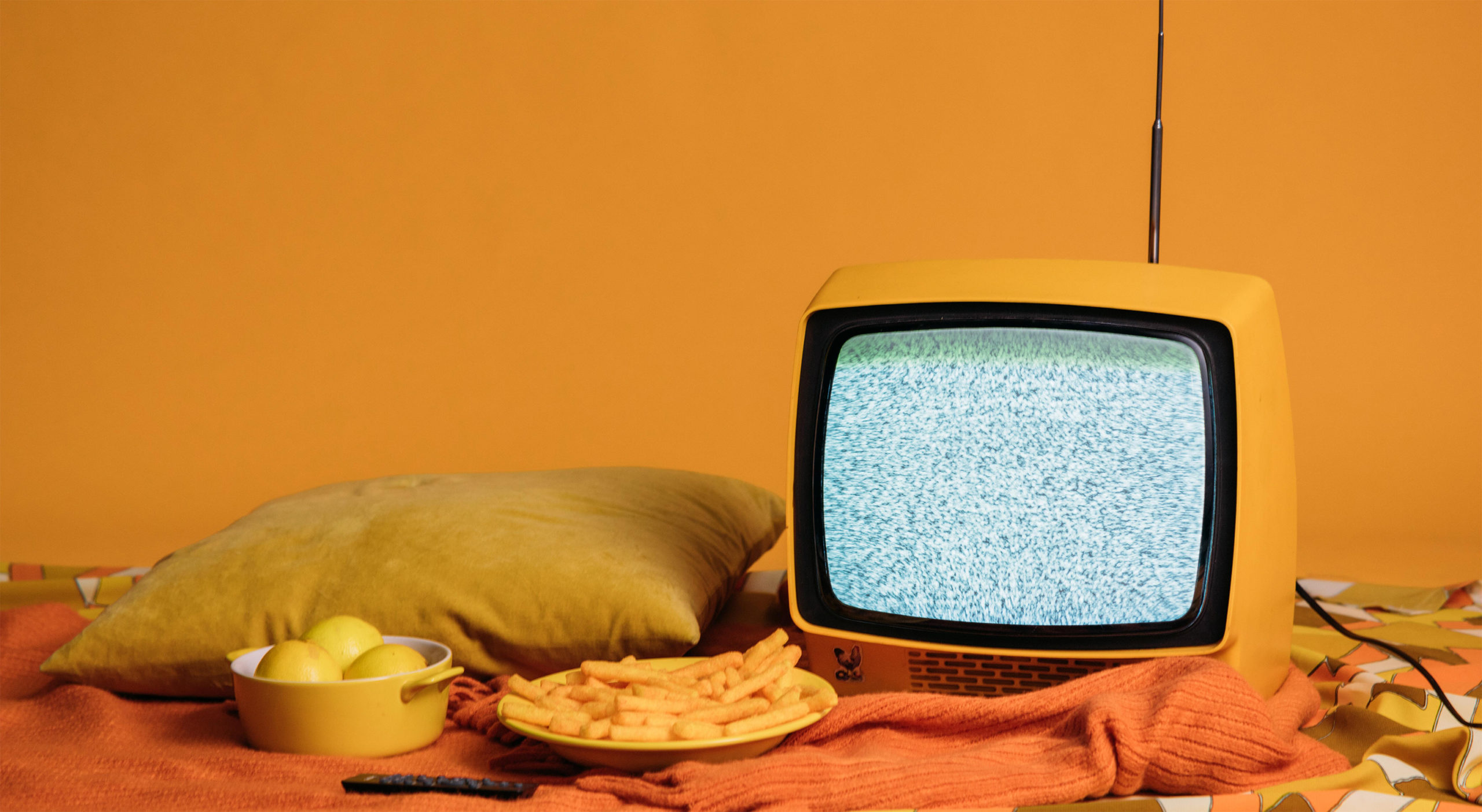 Photo of yellow television and snacks with orange background