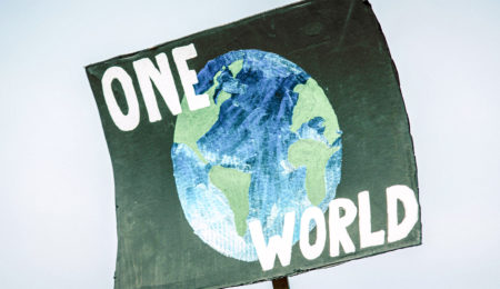 Photo of black poster with a drawing of a planet with the words "One World" surrounding the planet image