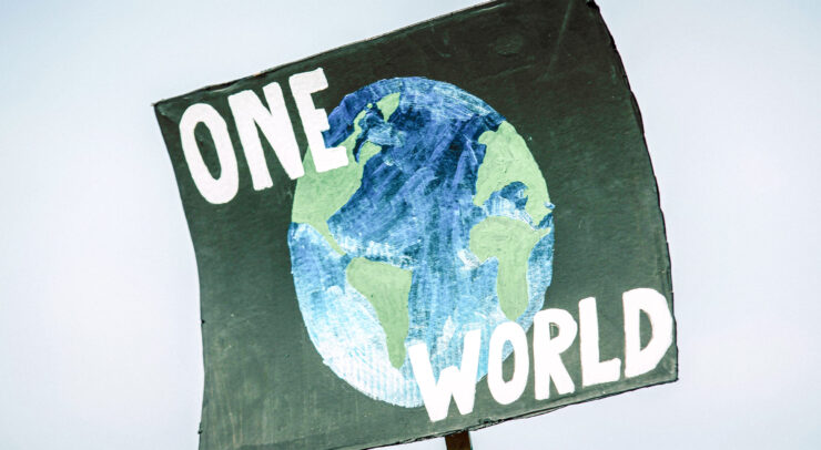 Photo of black poster with a drawing of a planet with the words "One World" surrounding the planet image