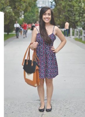 Student posing on campus wearing a spotted blue, red, and white dress
