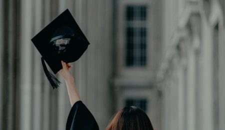 Photo of a girl holding a graduation cap in the air