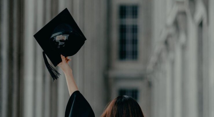 Photo of a girl holding a graduation cap in the air