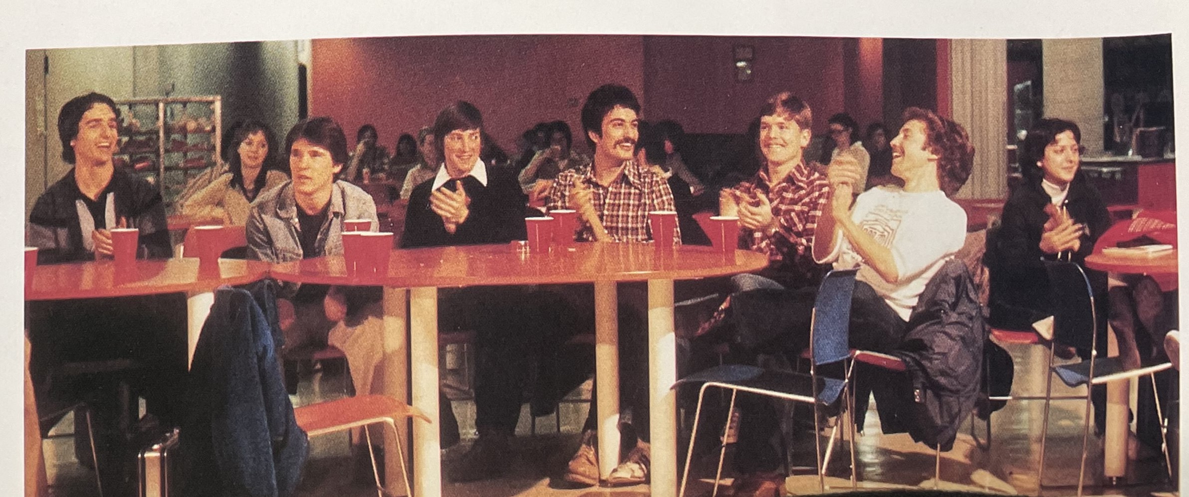 A group of students sitting at a table smiling and laughing.