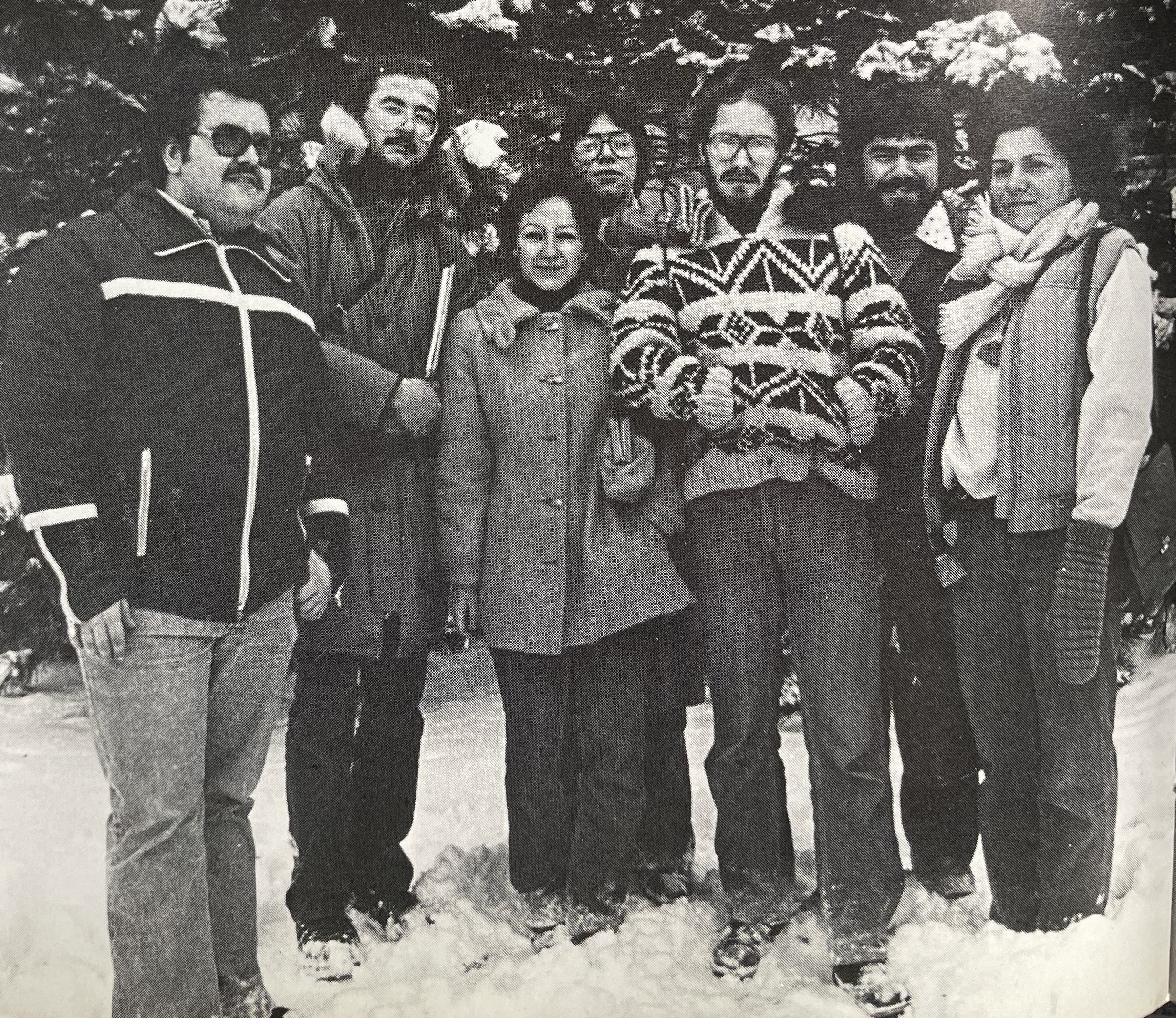 Group of students posing outside against snowy background wearing winter jackets. 