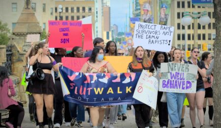Participants of the SlutWalk hold up signs as they chant in protest.