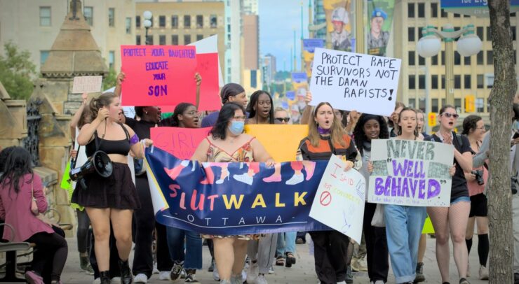 Participants of the SlutWalk hold up signs as they chant in protest.