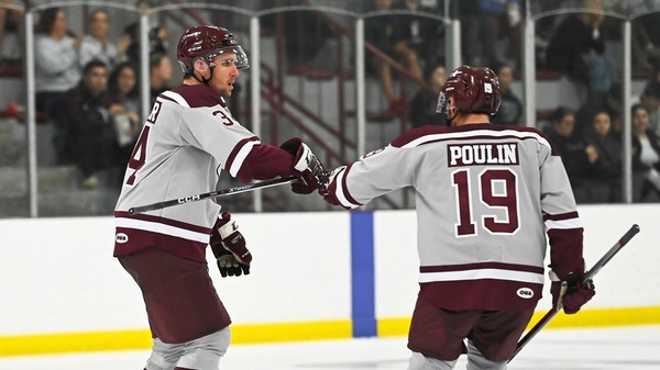 Two Gee-Gees hockey players bump fists on the rink.