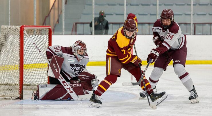 concordia forward handles the puck with her back turned towards the Gee-Gees goalie