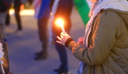 A student holds a candle at a vigil for Palestinian martyrs.