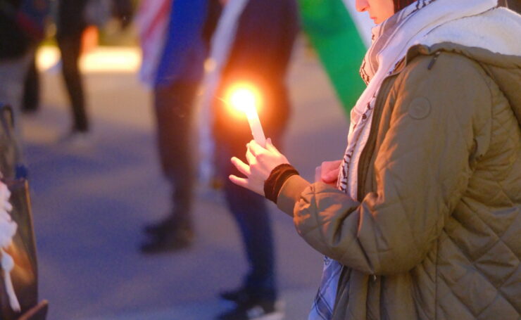 A student holds a candle at a vigil for Palestinian martyrs.