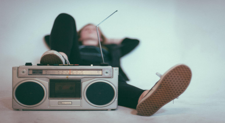 person laying back and listening to music with their foot resting on a radio