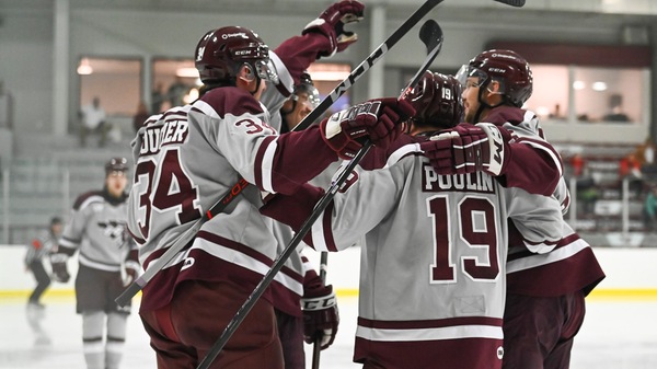 Group of male hockey players hug each other on ice