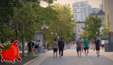 A photo of people walking across a university campus with a tomato logo in the corner