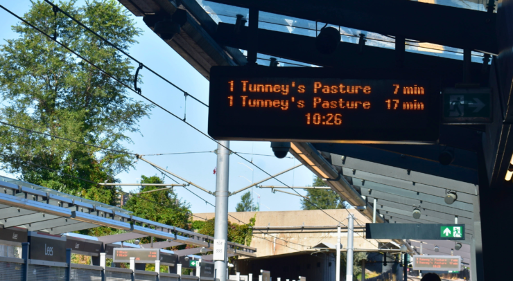 A sign with light rail wait times: “tunney’s pasture comes in 7 mins; tunney’s pasture comes in 17 mins”