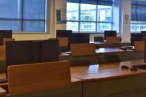 Multiple rows of computer screens sitting on desks