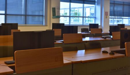 Multiple rows of computer screens sitting on desks