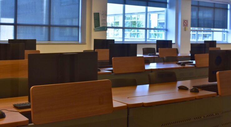 Multiple rows of computer screens sitting on desks