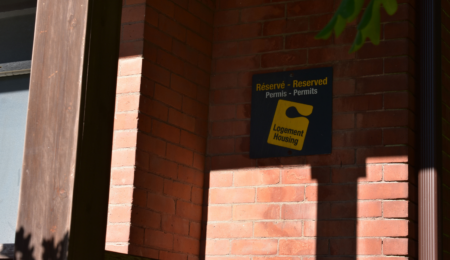 A U of O housing sign on a brick wall.