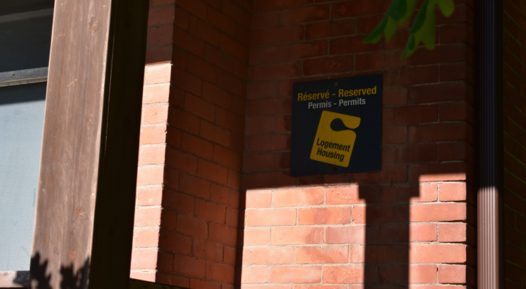 A U of O housing sign on a brick wall.