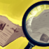 A graphic done by Noah Holun depicting a magnifying glass over a newspaper.