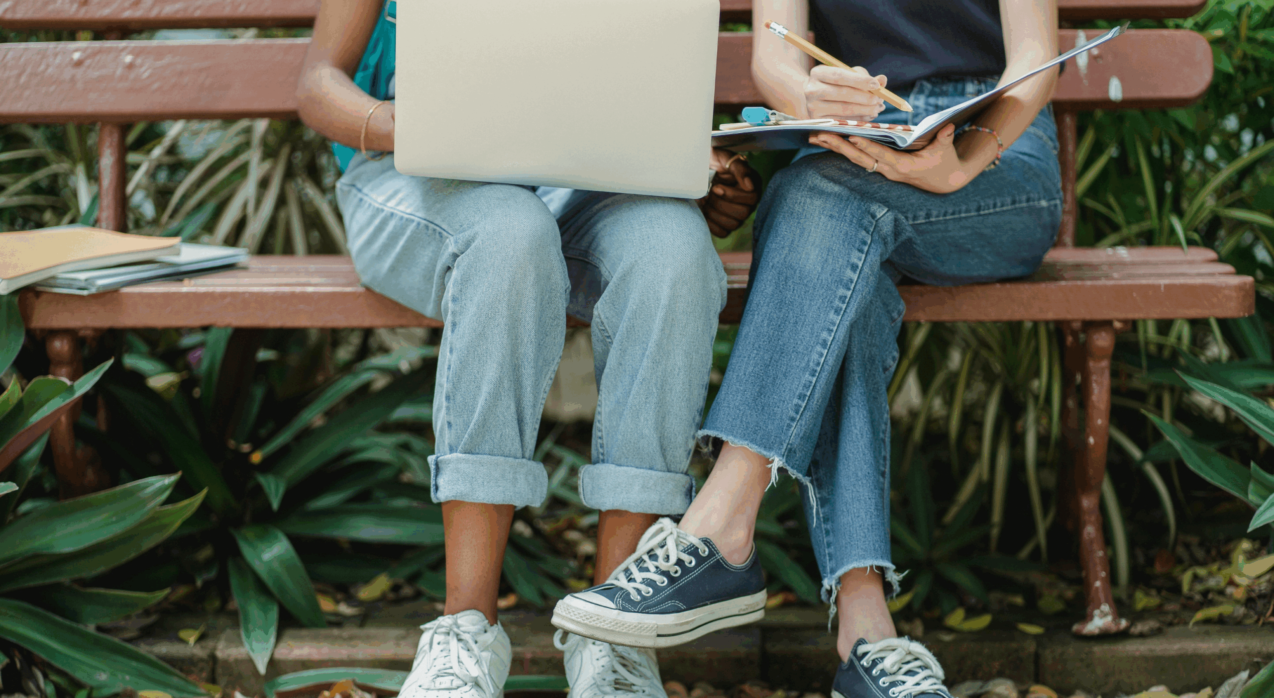 Two people on a bench studying and look at notes.