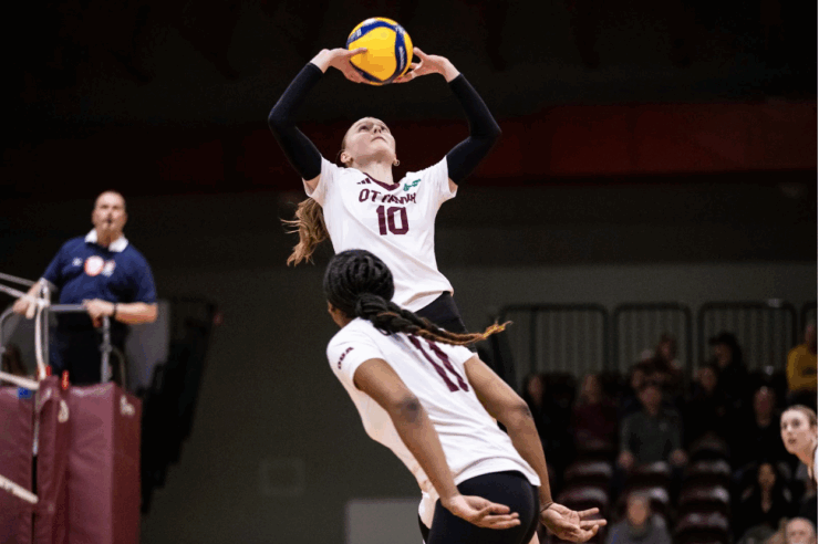 Gee-Gees setter Harper Schaefer with the ball in her hands above her head, about to set